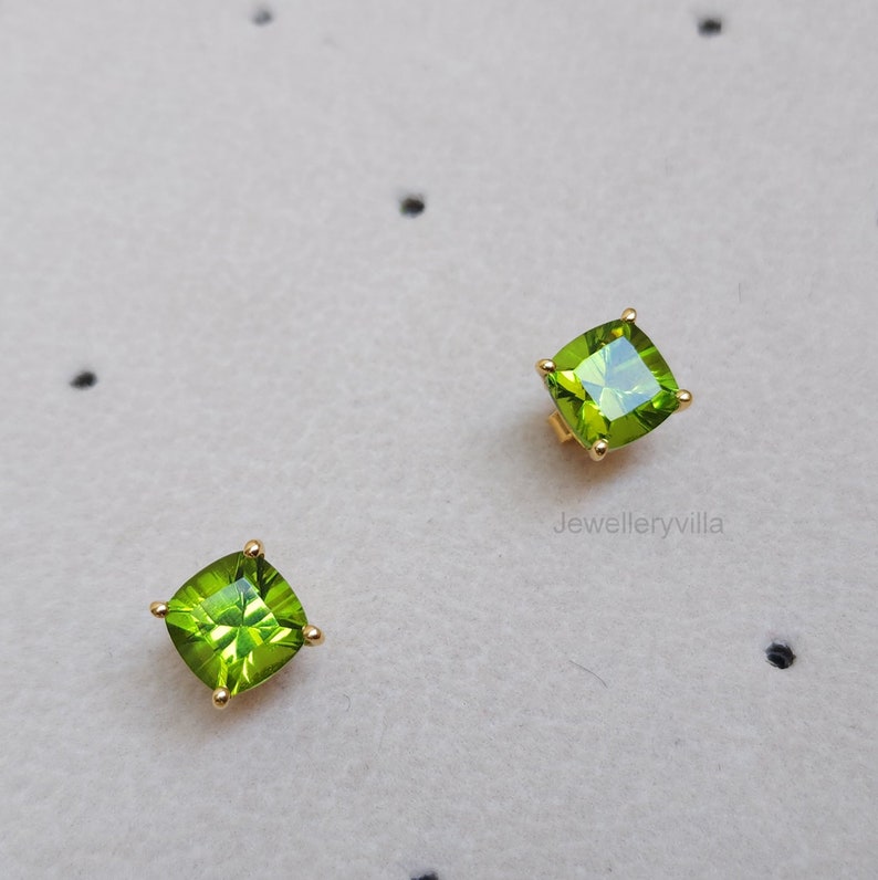 May include: A pair of gold earrings with square green peridot gemstones.