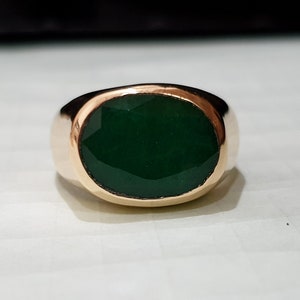 Könnte beinhalten: Ein goldener Ring mit einem großen, ovalen, grünen Edelstein.