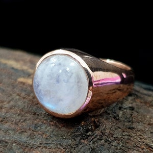 Puede incluir: Un anillo de oro rosa con una gran piedra de luna redonda y blanca.