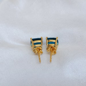 Puede incluir: Un par de pendientes de oro con detalles de piedras preciosas azules. Los pendientes tienen cierre de poste.