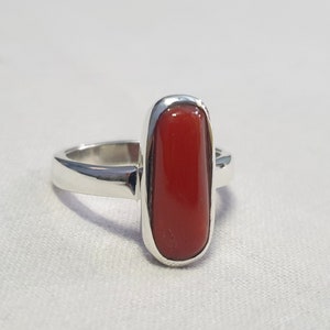 May include: A silver ring with a rectangular red coral gemstone.