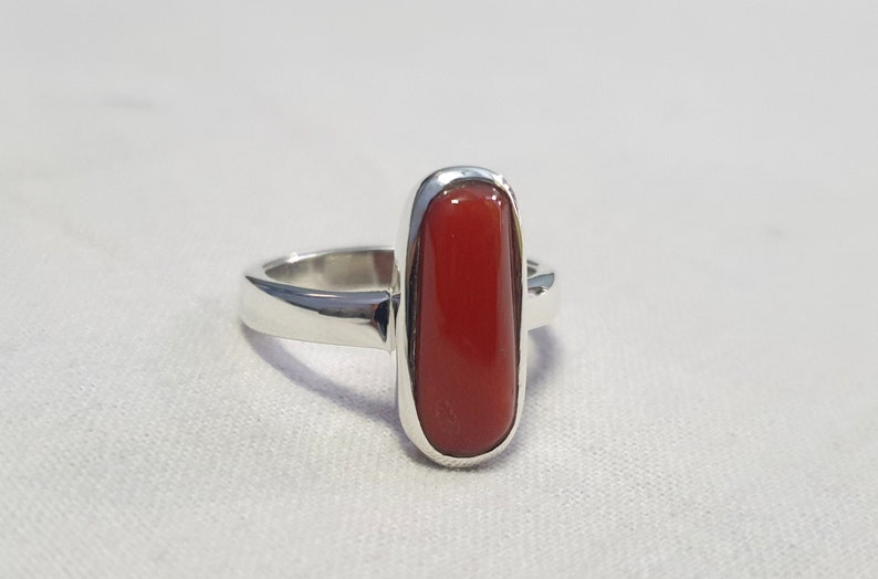 May include: A silver ring with a rectangular red coral gemstone.