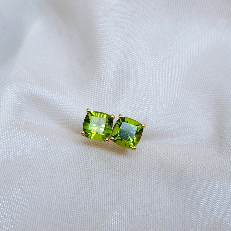 May include: A pair of gold earrings with square green peridot gemstones.