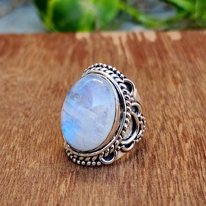 May include: A silver ring with a large oval moonstone set in a detailed filigree design.