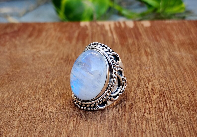 May include: A silver ring with a large oval moonstone set in a detailed filigree design.