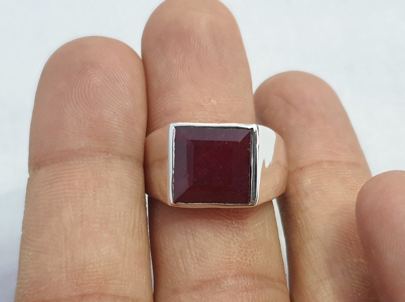 Peut inclure: Une bague en argent avec une pierre carr&eacute;e rouge fonc&eacute;.
