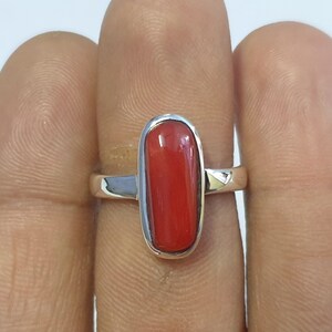 May include: A silver ring with a red oval-shaped gemstone.