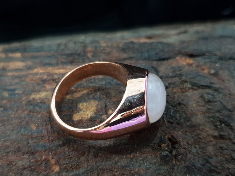 Puede incluir: Un anillo de oro rosa con una piedra ovalada blanca.