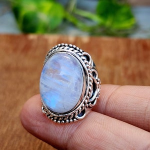 May include: A silver ring with a large oval moonstone set in a detailed silver band.