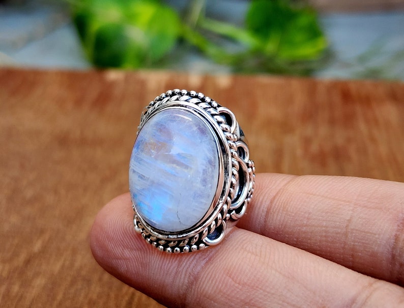 May include: A silver ring with a large oval moonstone set in a detailed silver band.