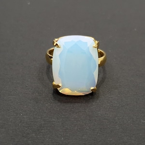 Può includere: Un anello d'oro con un grande opale sfaccettato trasparente.