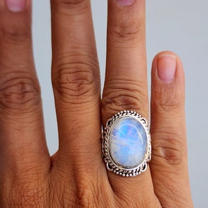 May include: A silver ring with a large oval moonstone set in a detailed silver band.