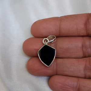 May include: A black onyx pendant in a silver shield shape with a silver bail.