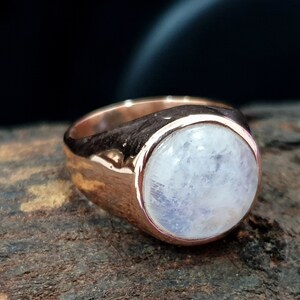 Puede incluir: Un anillo de oro rosa con una gran piedra de luna redonda y blanca.