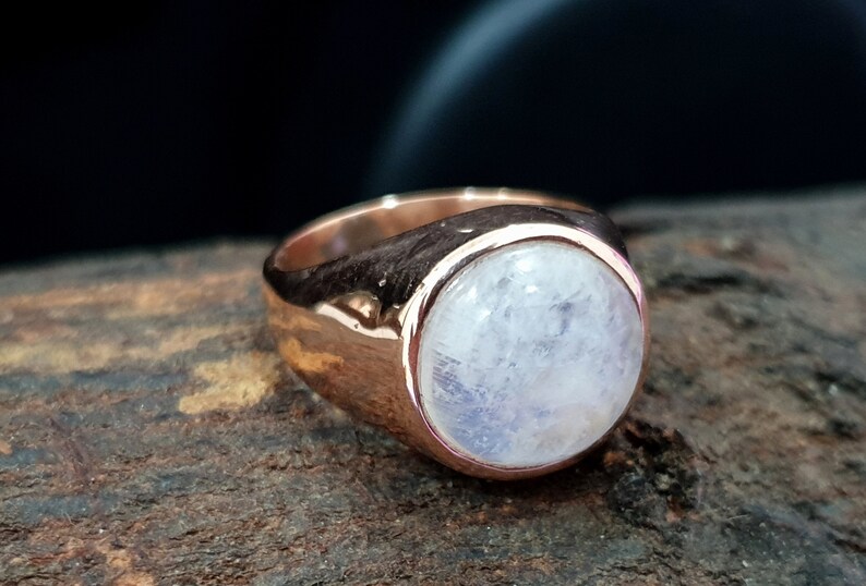 Puede incluir: Un anillo de oro rosa con una gran piedra de luna redonda y blanca.