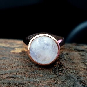 Puede incluir: Un anillo de oro rosa con una gran piedra de luna redonda y blanca.
