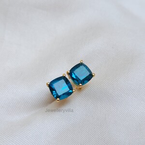 Puede incluir: Un par de pendientes de oro con piedras azules cuadradas.