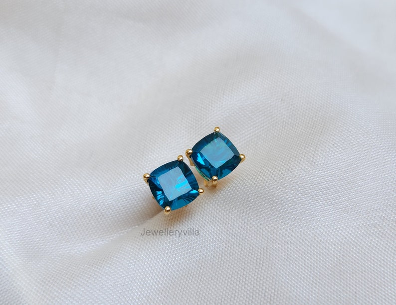 Puede incluir: Un par de pendientes de oro con piedras azules cuadradas.