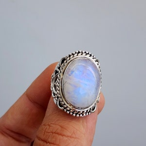 May include: A silver ring with a large oval moonstone set in a detailed filigree design.