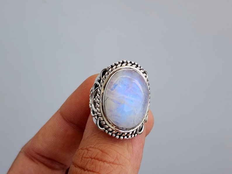 May include: A silver ring with a large oval moonstone set in a detailed filigree design.