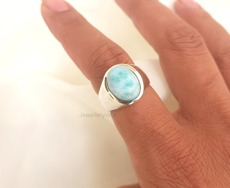 K&ouml;nnte beinhalten: Ein silberner Ring mit einem ovalen, hellblauen Edelstein. Der Edelstein hat ein marmoriertes Muster.