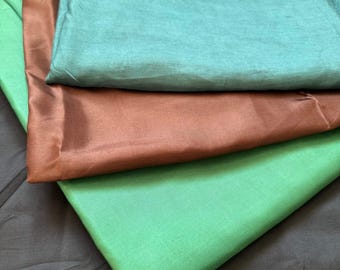 May include: Four different fabric swatches in teal, brown, green, and black. The swatches are folded and layered on top of each other.