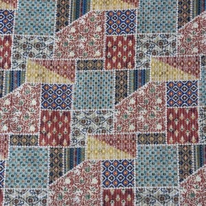 Op de afbeelding: Een patchwork textiel met een geometrisch patroon van vierkanten en driehoeken. Het ontwerp gebruikt verschillende kleuren, waaronder rood, blauw, geel en beige, met gedetailleerde bloemen- en geometrische motieven. De stof lijkt aan elkaar gestikt.
