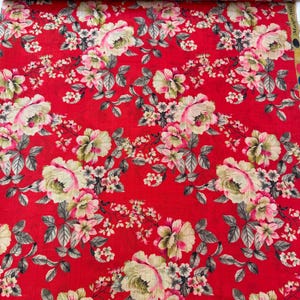 May include: Red floral fabric with a repeating pattern of cream and pink roses, complemented by green and grey foliage. The design includes smaller blossoms, creating a detailed and vibrant textile.
