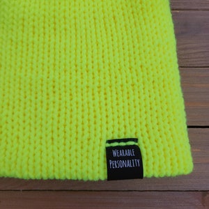 May include: A bright yellow knitted beanie with a black label that reads "Wearable Personality".