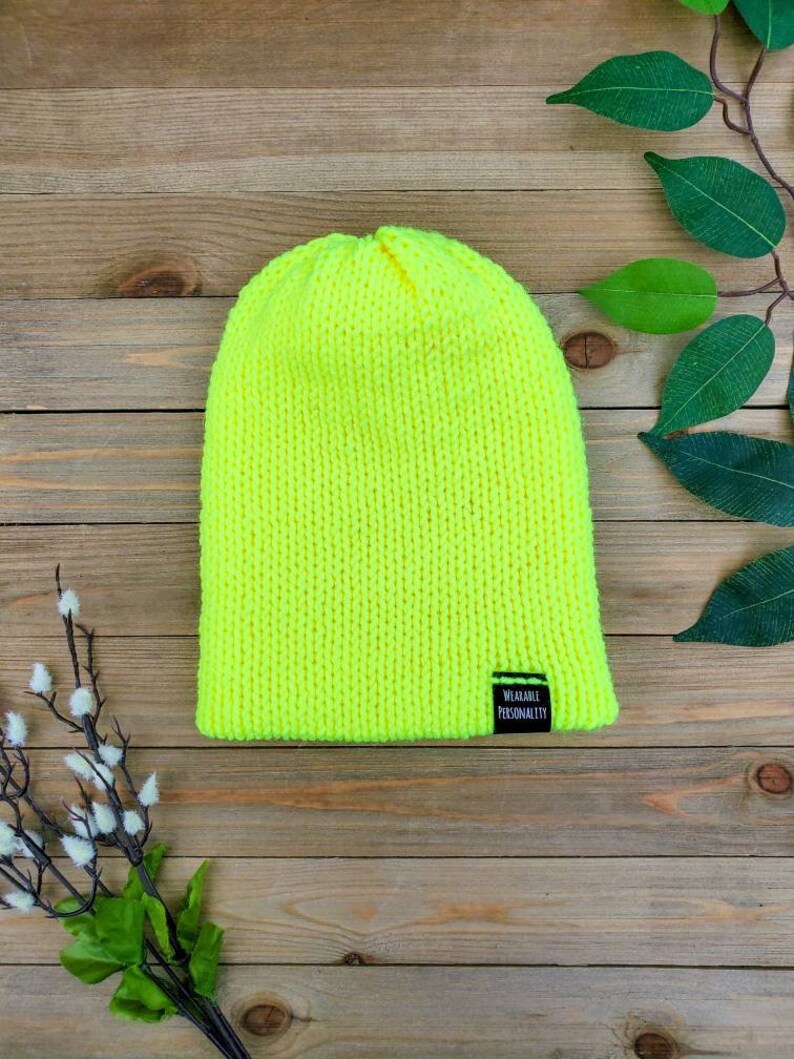 May include: A bright neon yellow knitted beanie with a black label that reads "Wearable Personality".