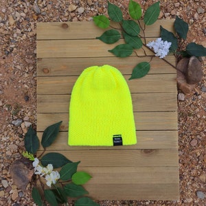 May include: A bright neon yellow knitted beanie with a black label that says "WARRIOR" on it.
