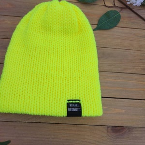 May include: A bright yellow knitted beanie with a black label that reads "Wearable Personality".