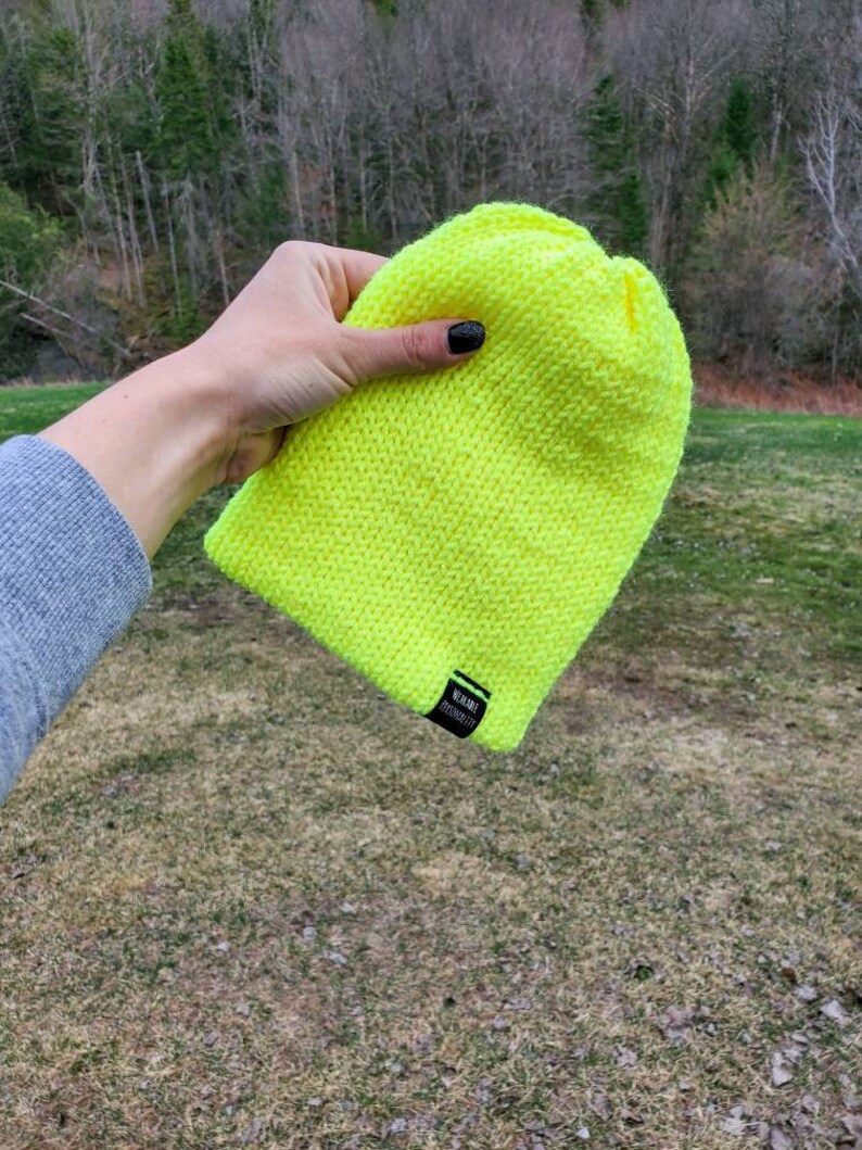 May include: A bright neon yellow knit beanie with a black label that reads "WURDE PROJECTED".