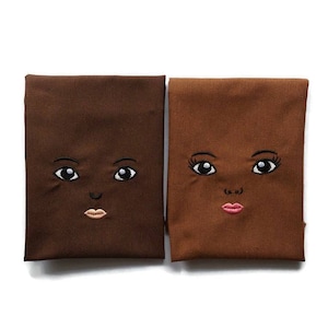 Embroidered face for African rag doll.