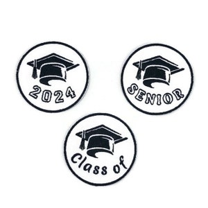 Op de afbeelding: Drie witte ronde strijklabels met zwarte borduursels. De labels tonen een afstudeerhoed met kwast en de tekst "2024", "Senior" en "Class of".