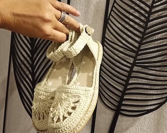 May include: A pair of beige crocheted sandals with a star pattern. The sandals have a closed toe and an ankle strap.