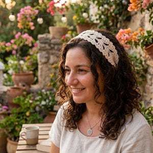 Könnte beinhalten: Ein cremefarbenes Häkel-Stirnband mit einem sich wiederholenden blattartigen Muster. Das Accessoire ist aus Garn mit einer sichtbaren Textur und einem komplexen Lochmuster gefertigt und dazu bestimmt, um den Kopf getragen zu werden.