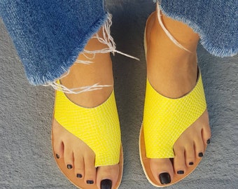 May include: A pair of yellow leather sandals with a toe thong design. The sandals have a simple, minimalist style and are perfect for warm weather.