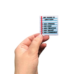 May include: A white patch with blue and red lines, featuring the text "MY NAME IS GRAYSON I AM STRONG I AM KIND I AM CREATIVE I AM SMART I AM CONFIDENT".