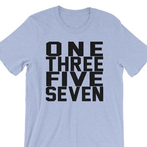 Pode incluir: Camiseta azul claro com texto preto que diz "ONE THREE FIVE SEVEN".