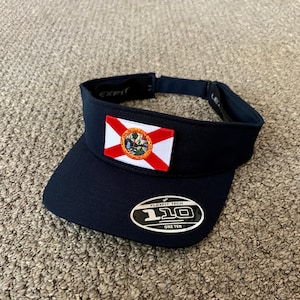 May include: A navy blue visor with a Florida state flag patch and a Flexfit Tech One Ten logo.
