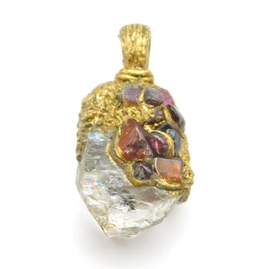 May include: A gold pendant featuring a clear quartz crystal with a cluster of red, orange, and purple gemstones set in the gold.