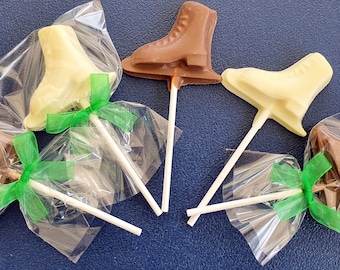 May include: Five chocolate ice skate lollipops wrapped in clear plastic bags with green ribbon bows. The lollipops are in two colors: white chocolate and milk chocolate.