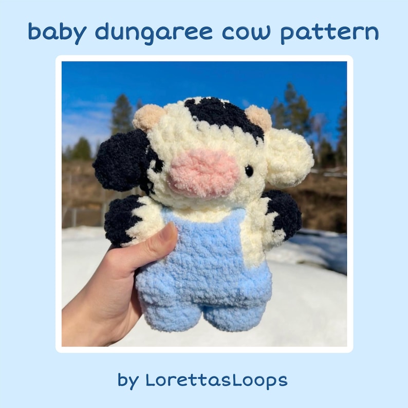 May include: A crocheted cow plush toy wearing blue overalls. The cow has black and white spots and a pink nose. The toy is being held by a hand.