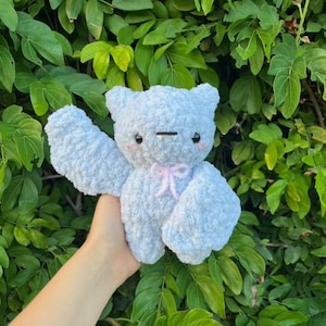 May include: A light blue plush toy bear with a pink bow. The bear has a stitched smile and large, black eyes.