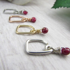 May include: Four different colored wire wrapped rings with a small red gemstone attached to each ring.