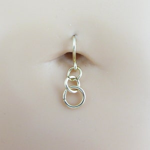 May include: Gold belly button ring with a chain and three connected rings dangling from it.