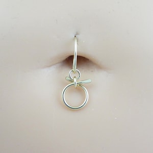 May include: Gold belly button ring with a small circle and a curved bar attached to the top.