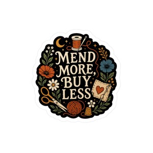 May include: A die-cut sticker with a black background featuring the text MEND MORE, BUY LESS in cream. Illustrations include a spool of thread, scissors, a ball of yarn, a thimble, a needle, a fabric patch with a heart, and various flowers.