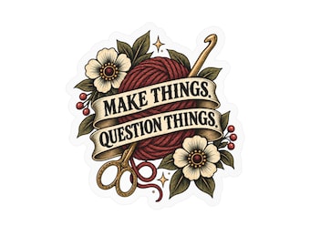 Könnte beinhalten: Ein Aufkleber mit einem dunkelroten Wollknäuel, einer goldenen Häkelnadel und einer goldenen Schere. Ein beiges Banner in der Mitte zeigt den schwarzen Text "MAKE THINGS. QUESTION THINGS.". Das Design wird durch weiße Blumen, grüne Blätter, rote Beeren und kleine vierzackige Sterne ergänzt.